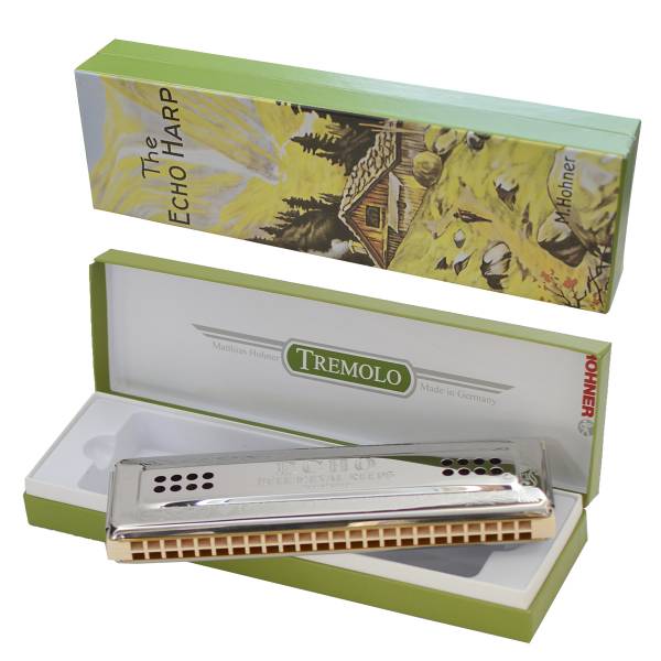 Hohner Echo double-sided harmonica in the bottom of a green retail box, with the box lid featuring a mountain landscape illustration displayed above it.