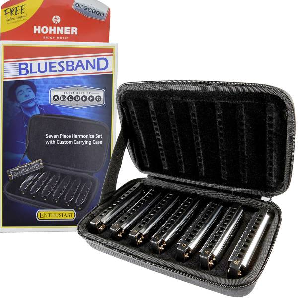 Seven Hohner Bluesband harmonicas neatly arranged in an open black zippered case, positioned in front of the retail box featuring an illustration of a harmonica player.