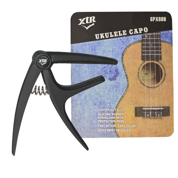 A black XTR GPX60B trigger-style ukulele capo positioned next to its retail display card, which features a printed illustration of a ukulele and product specifications.