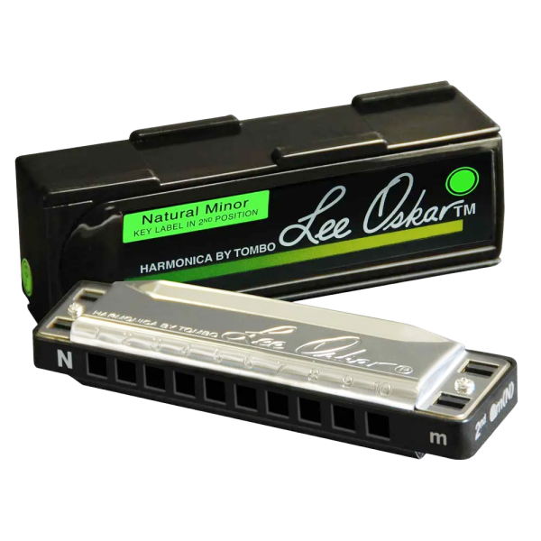 A Lee Oskar Natural Minor harmonica with an "N" stamped on the silver cover plate, resting in front of a black case with a green label.