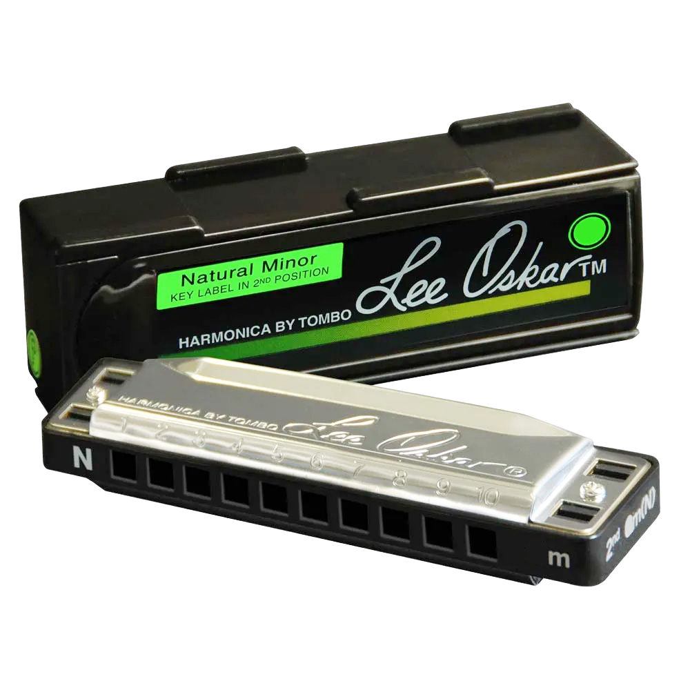 A Lee Oskar Natural Minor harmonica with an "N" stamped on the silver cover plate, resting in front of a black case with a green label.