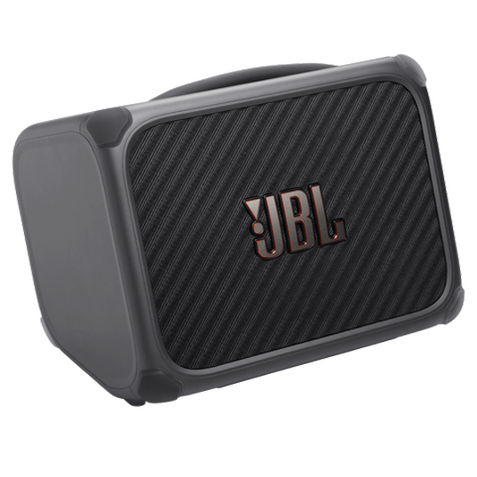 A dark grey rectangular portable speaker positioned at a slight angle. The speaker features rounded edges fitted with smooth, protective rubber corner bumpers and an integrated carry handle along the top. The front panel consists of a dark, diagonally ribbed mesh grille, accented by a raised metallic JBL logo in the center.